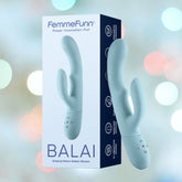 A box of the Femme Funn Balai Rabbit Vibrator - Light Blue, shown with the product next to the packaging. The light blue vibrator from Femme Funn features 12 vibration modes and control buttons on the handle. The waterproof design is highlighted on the packaging, which also showcases other product features. The background is blurred and multicolored.